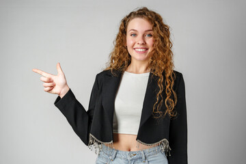 Smiling Young Woman Pointing While Posing in a Studio
