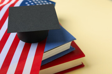 Graduate hat and books and american flag, on red background.