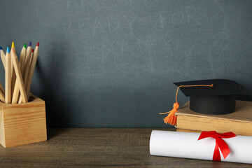 Graduation hat with books on a table on a dark background.