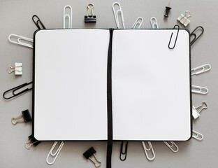 close up of notepad with blank pages and various type of paper clips over grey - Powered by Adobe