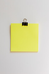 close up of yellow sticky note with paperclip over white