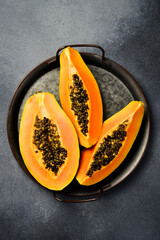 Tropical fruit papaya. Sliced ripe papaya fruit on a metal tray. Top view.