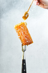 A honey stick with honey in a woman's hands watering the honeycombs. Honey and beekeeping products.