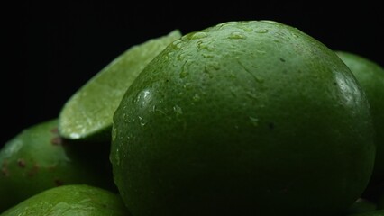 Slices of lime are meticulously arranged in a pile, set against a black background. Each lime slice...