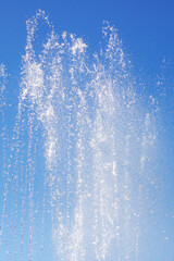 Liquid spraying from fountain against electric blue sky in natural landscape