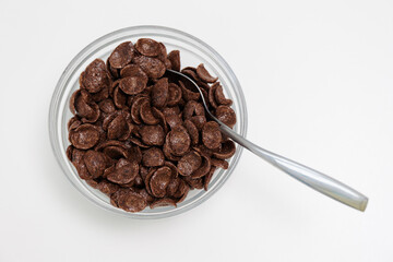 Choco cereals served in glass bowl with spoon on white