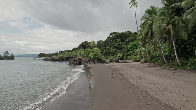Blonde woman running along a wild tropical beach alone