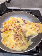 cooking egg with sausages turn over with a spatula in frying pan on stove.