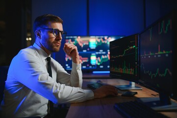businessman comparing stock market data late in the evening