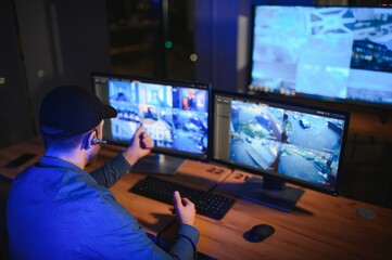 Male security guard monitoring modern CCTV cameras indoors