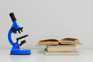 Blue microscope and books on table