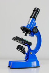 Side view of blue microscope on white table