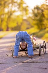 Fototapeta premium Cute beautiful schoolchild, playing with little gosling in a park on sunset