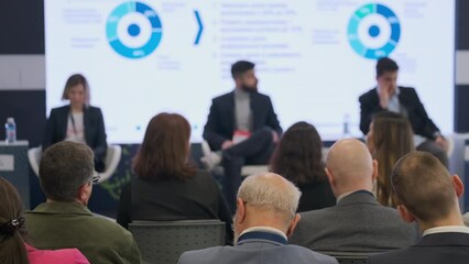A business conference scene showing a panel discussion with three panelists and a keenly listening audience. Focus on engaging corporate events.