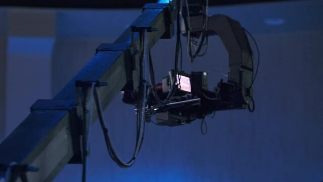 A professional video camera mounted on a crane captures footage in a dark studio environment, highlighting advanced filming technology and expertise in media production.