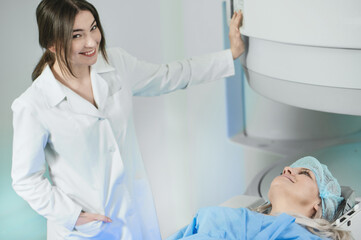 Naklejka premium Woman doctor and patient in the MRI room. female assistant preparing adult female patient for MRI scan 