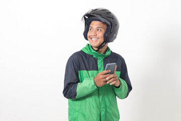 Portrait of Asian online taxi driver wearing green jacket and helmet holding mobile phone with smiling expression face. Isolated image on white background