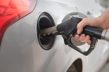 Man refueling the car at a gas station. Close-up of driver hand pumping gasoline car with fuel at...