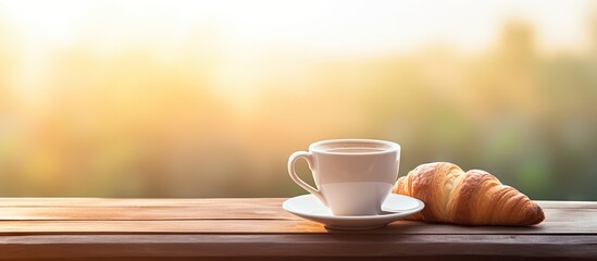 A coffee cup and a buttered fresh French croissant are placed on a wooden crate creating a food and breakfast concept A white board nearby displays the morning message have a nice day offering a visu - Powered by Adobe