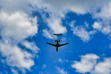 Business jet on blue sky with clouds from below