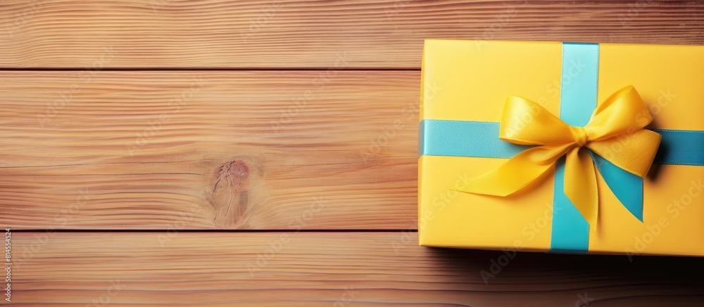 Poster a stunning gift box adorned with a colorful bow rests on a vibrant yellow wooden table captured from
