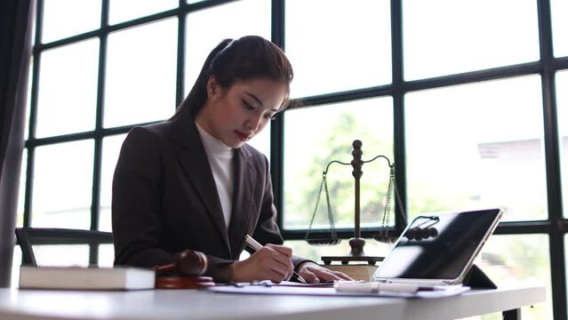 Serious female lawyer working on paperwork in law office, she is reading and signing contract agreement.