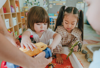 Children playing with toy animal figures in bulk cereals and pasta with teacher in kindergarten