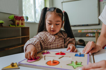 Girl and teacher playing with educational wooden toys in a kindergarten
