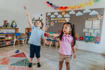 Boy and girl playing with musical rattles in kindergarten