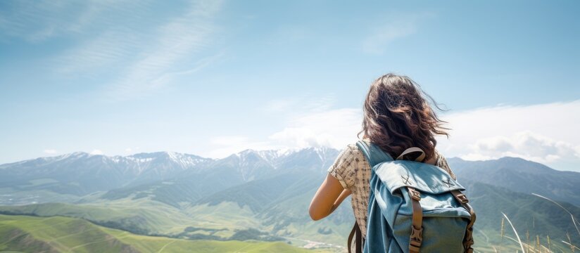 Copy space image of a cheerful teenage girl with a backpack experiencing joy while gazing at the scenic mountain view This background represents the concept of a summer vacation hike