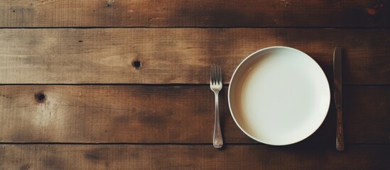 A modern style square plate with a stainless steel fork and a white milk jar sits on an old wooden...