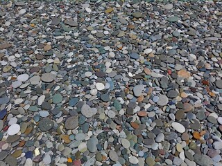 Perspective of rounded Sea Pebble stones and rocks on beach as natural abstract pebble texture or background. Random small multicolor pebble stones. Close up colorful Pebble stones or gravel on coast.