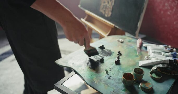 Woman artist dips brushes into paint
