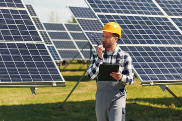Communication by using walkie talkie. Engineer with photovoltaic solar panels outdoors at daytime