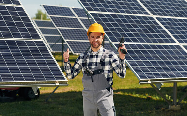 Drill in hand. Engineer with photovoltaic solar panels outdoors at daytime