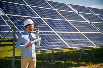 Professional adult engineer with photovoltaic solar panels outdoors at daytime