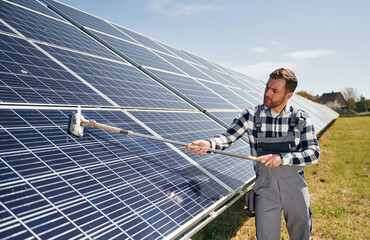 Process of cleaning the surface. Engineer with photovoltaic solar panels outdoors at daytime