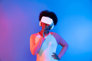 Profile thinking young beautiful African wearing VR glasses metaverse isolated on blue and pink neon lighting gradient background in technology and digital innovation 3D hologram graphic. Contrivance.