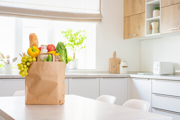 Paper bag full of food on table in modern kitchen interior with copy space