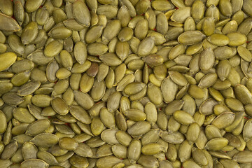 Close up photograph of green hulled or peeled pumpkin seeds without shell. Top view background.