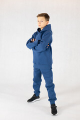 Cheerful boy in blue tracksuit on white background. Pretty boy,. Baby model. A little boy poses on a white background.