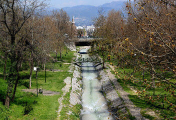 View of a park area with a river and an iron arch bridge across it and a mosque in the background...