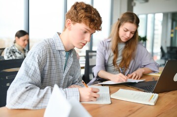 Obraz premium students sit at shared desk making notes studying together at university