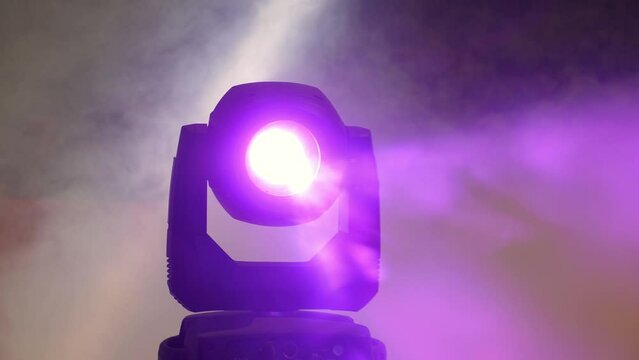 A close-up of a spotlight with purple light in the smoke at a concert or circus show. Professional lighting equipment. Circus background. Stable camera movement.