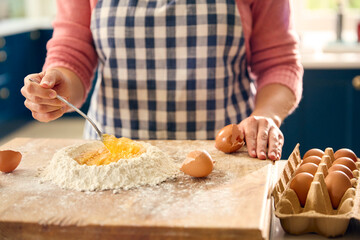 Close Up Of Woman At Home In Kitchen Mixing Eggs With Flour Making Dough On Worktop Or Counter
