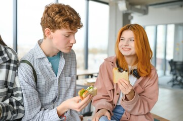 A group of young students having a lunch break together and eating sandwiches