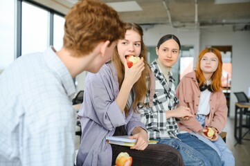 education, food, people and friendship concept, group of happy students eating apples