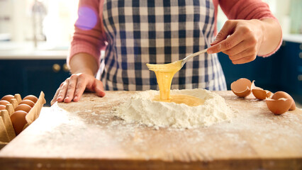 Close Up Of Woman At Home In Kitchen Mixing Eggs With Flour Making Dough On Worktop Or Counter