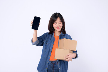 asian woman wearing orange t-shirt and denim shirt holding parcel box while showing a smartphone isolated on white studio background, Delivery courier and shipping service concept.