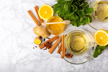 Fragrant hot tea with cinnamon stick and anise on a textured wooden background. A cup of hot tea with honey, lemon, mint and apples. Spicy tea with spices. Immunity tea. Health concept.Copy space.